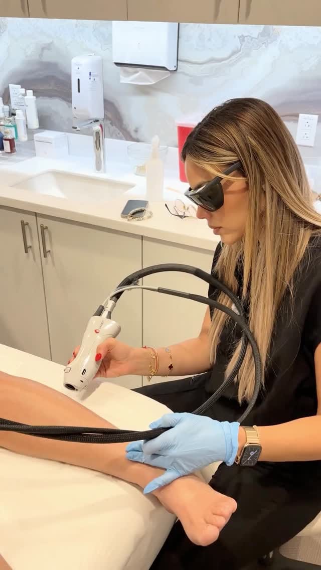 A provider in laser safety glasses treating a patient's arm with a laser handpiece