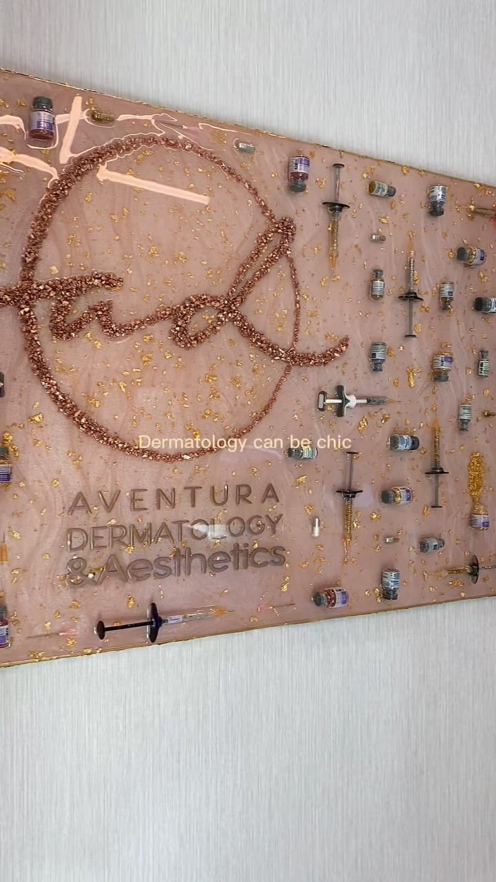 The Aventura Dermatology & Aesthetics logo on the office's decorated wall