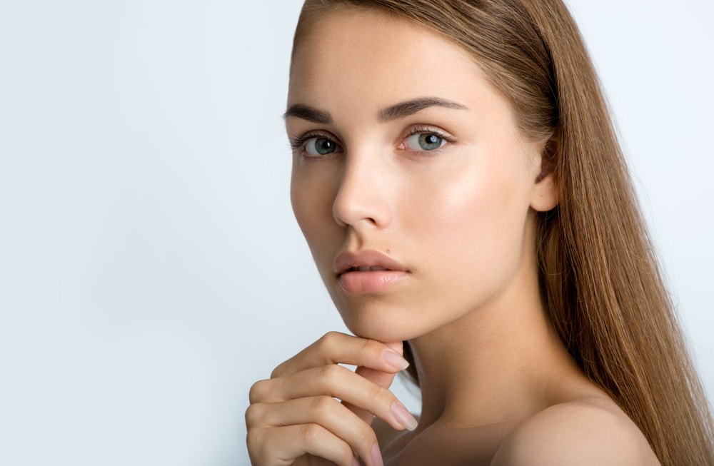 Model with clear, smooth skin resting her chin on her hand