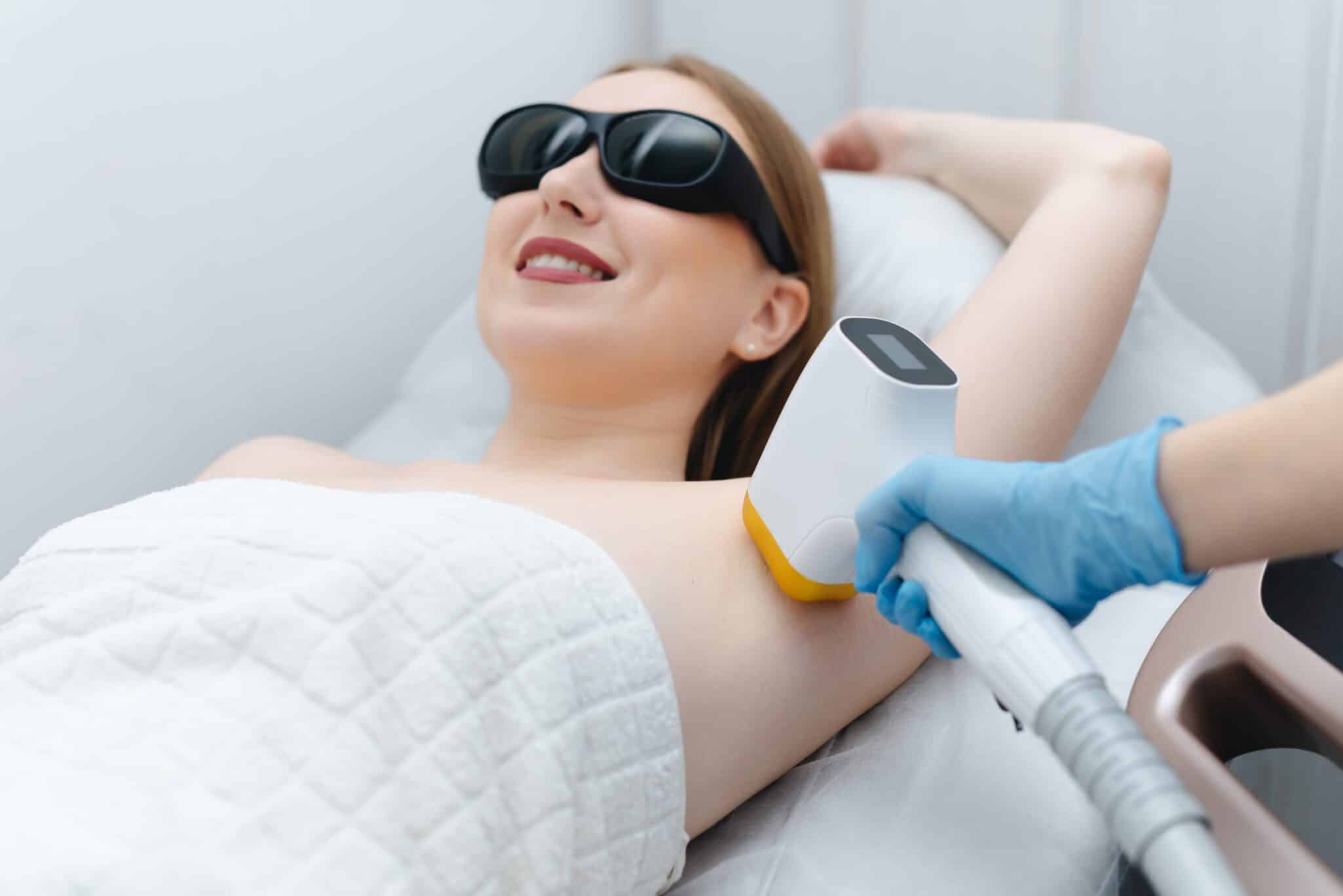 Model in protective goggles receiving laser hair removal on her underarm