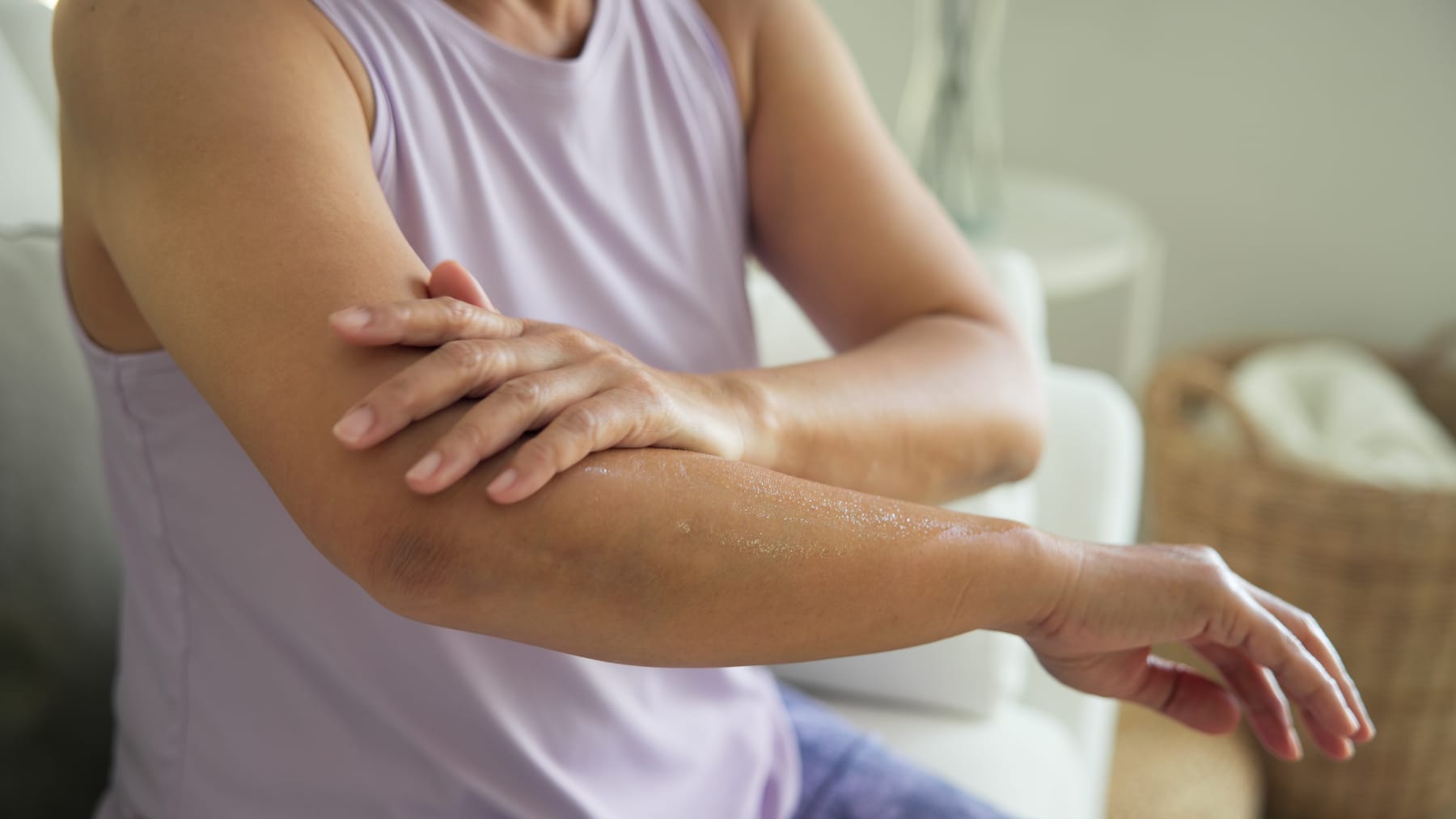 Smiling mature model applying moisturising cream to her arm and elbow