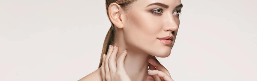 Model with her hair pulled back touching her neck, on a light background