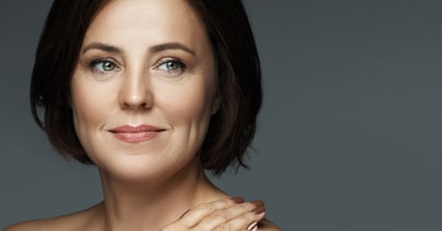 Model with a dark bob and clear skin, on a dark grey background