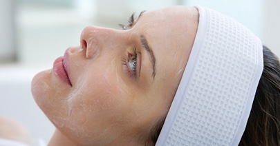 Model in a white headband with a chemical peel applied to her face