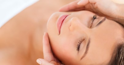 Model lying back with eyes closed during a facial