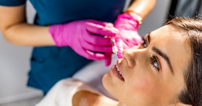 Clinician in pink gloves treating a model's face