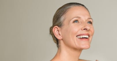 Smiling mature model with her hair pulled back, on a beige background