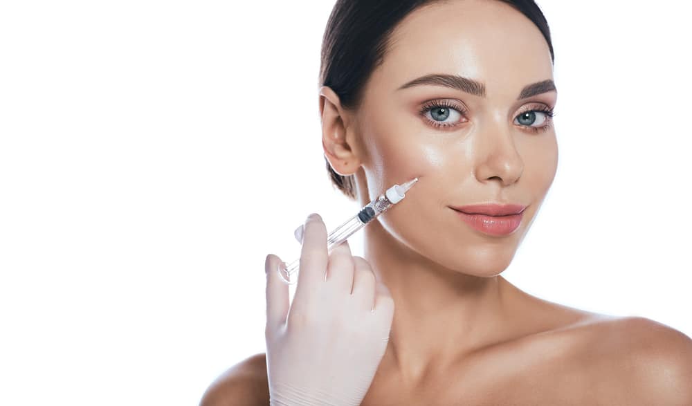 Beautiful woman happily receiving Juvederm dermal fillers to her cheeks for a younger, brighter look.