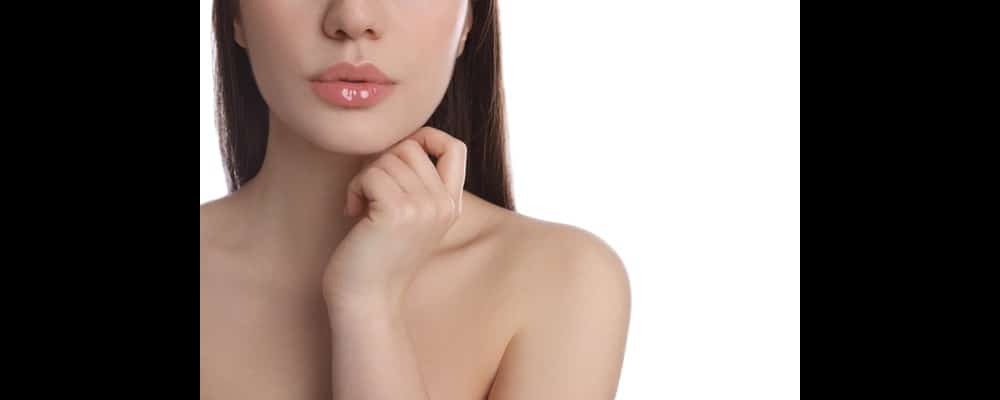 Close-up of a woman with full, glossy lips. She is prepared for Valentine's Day after getting lip treatment.