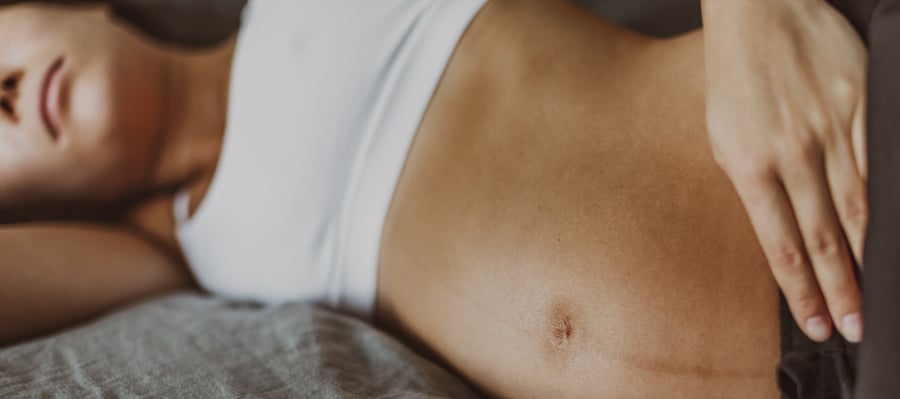 Pregnant woman lying in bed sad of depression or having or sleep problem. Closeup of belly skin with dark line from pregnancy symptom