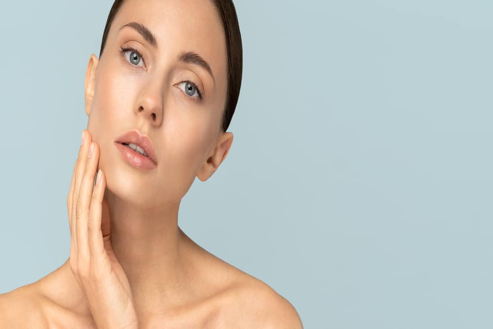 Woman touching her smooth, shining skin after getting IPL treatment for redness and uneven skintone