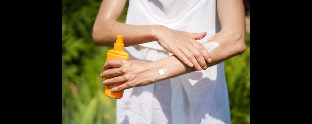 Close up of someone applying sunblock to their arms in an effort to protect from sun damage.